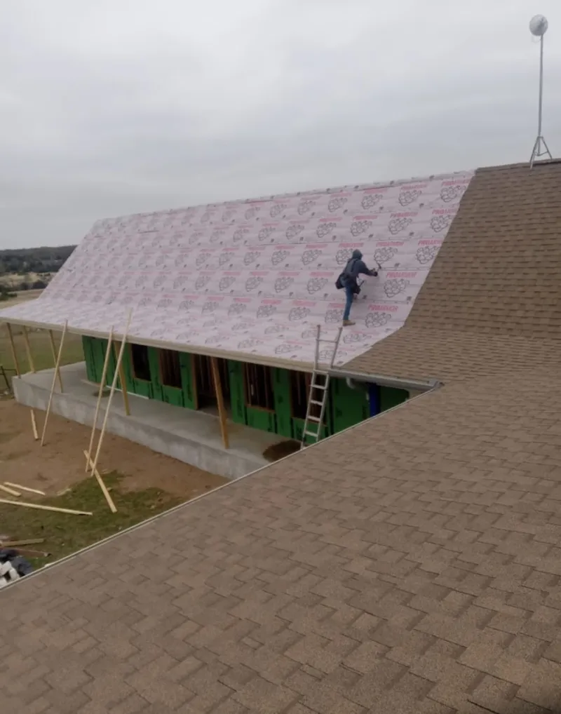 Worker preparing underlayment for a metal roof installation in Wanaque